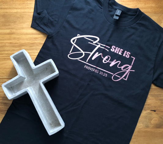 She Is Strong Tee – Metallic Pink on Black | Proverbs 31:25